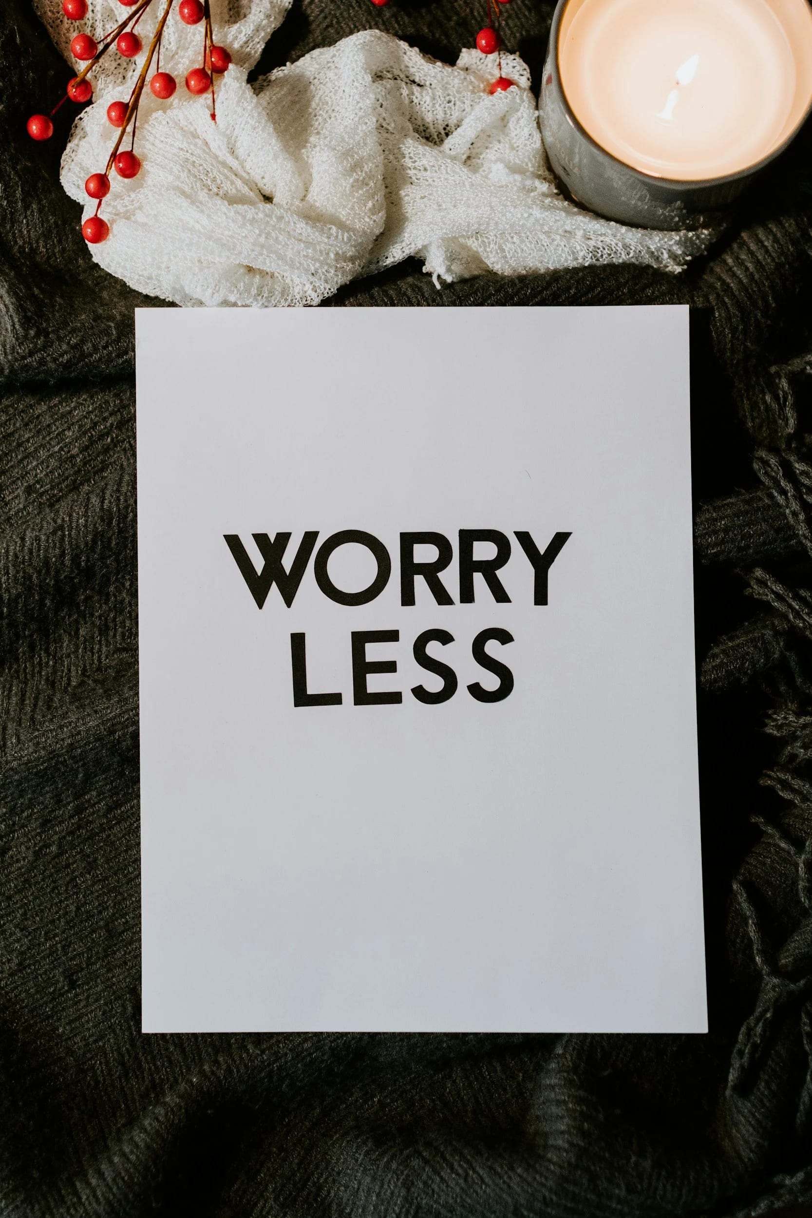 A printed card that reads "Worry Less" beside a lit candle
